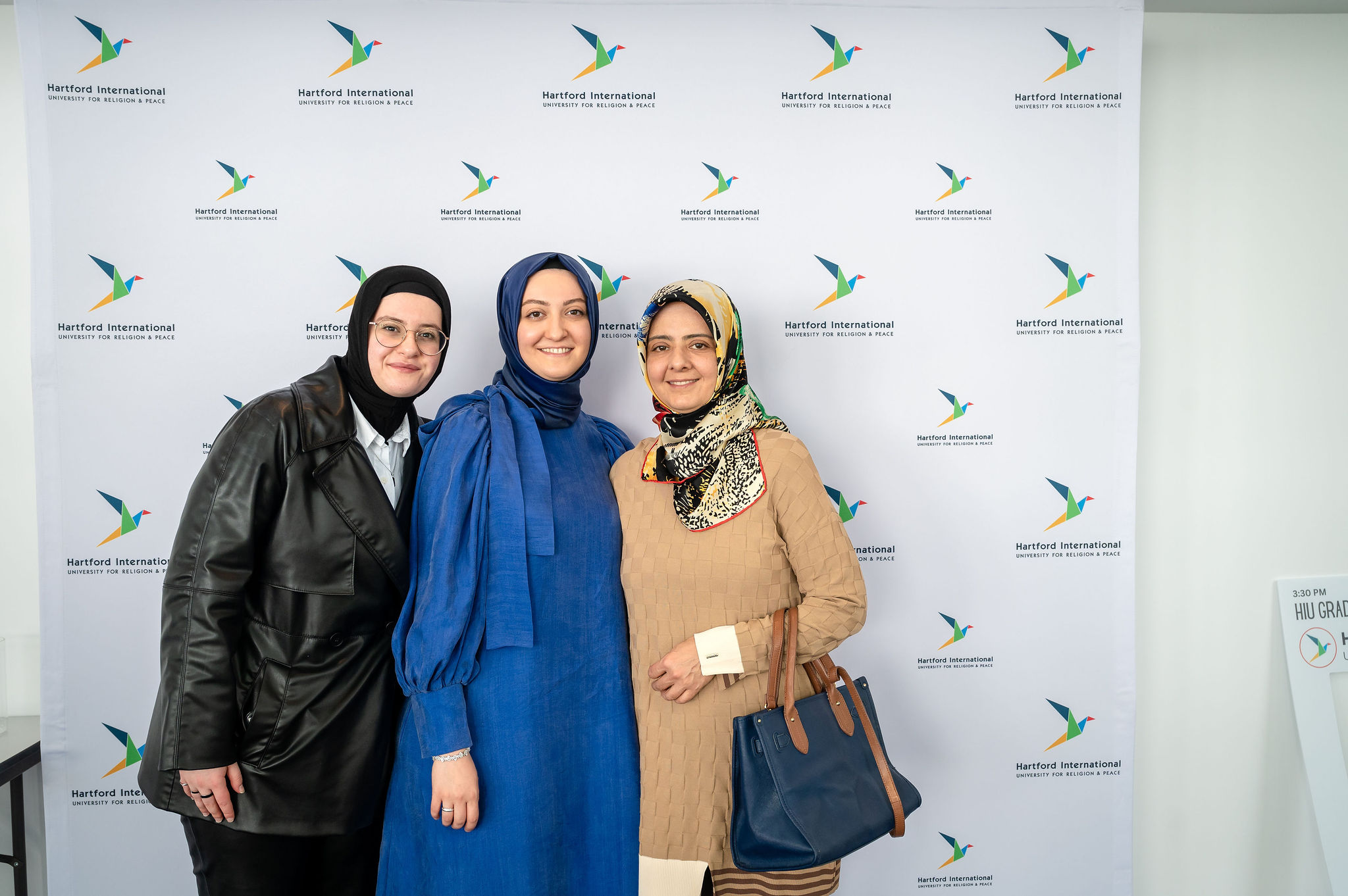 3 women in hijab in front of HIU banner
