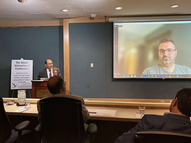 Man at podium talking to man on zoom screen